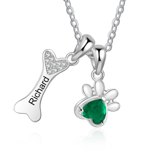 Custom pet paw and bone necklace with engraved name and birthstone.
